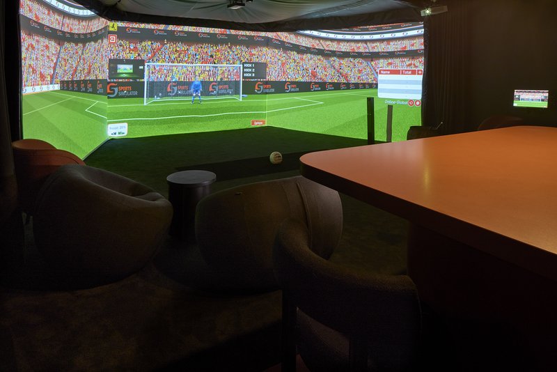 Game room with football simulator screen, brown leather seating and wooden table