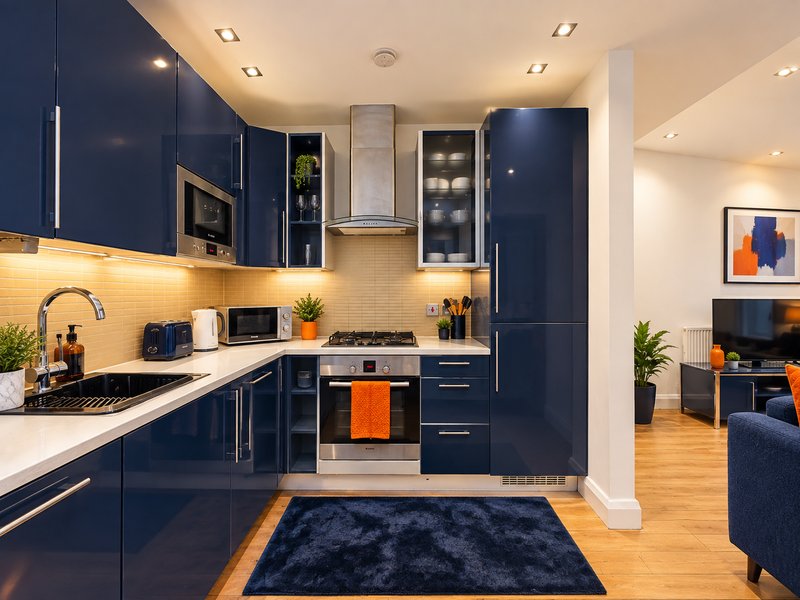Modern kitchen with navy cabinetry, white countertops, stainless steel appliances and wooden flooring