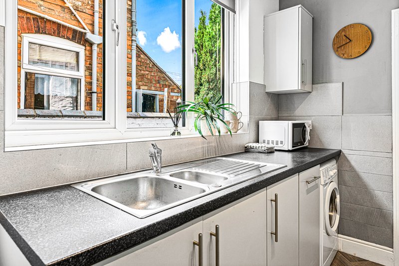 Modern kitchen with sink, black countertop, white appliances and window overlooking brick buildings