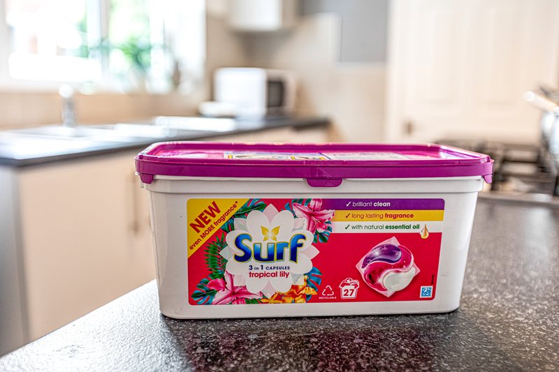 Kitchen countertop with laundry detergent container and white mug in background