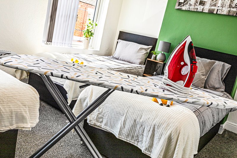 Bedroom with two single beds, green accent wall, ironing board and red iron