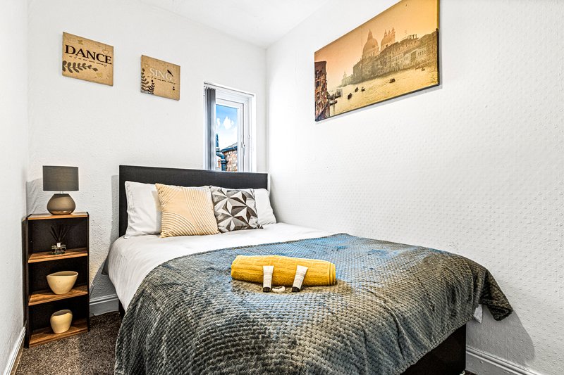 Compact bedroom with single bed, black frame, wooden side table and wall art