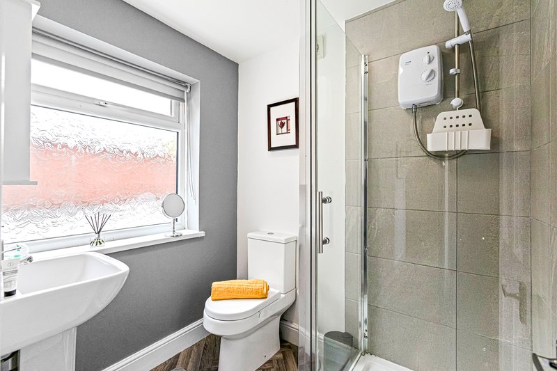 Bathroom with sink, toilet, shower cubicle, window and towel rack
