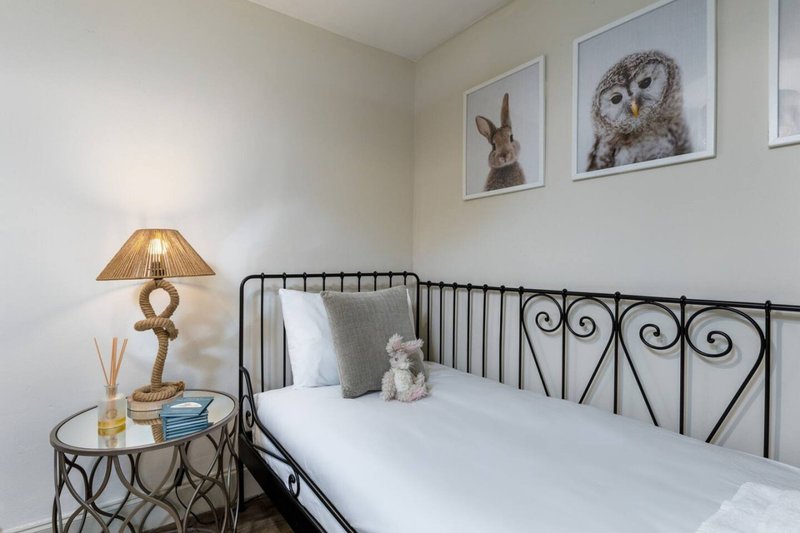 Bedroom with black metal bed frame, white bedding, decorative pillows, and framed wildlife artwork on wall