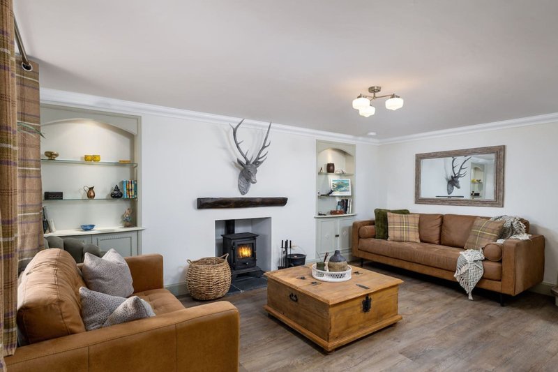 Spacious living room with brown leather sofas, wood coffee table, fireplace and built-in shelving