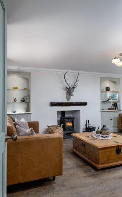 Living room with tan leather armchair, wood storage trunk, fireplace with antler mount, and built-in shelving