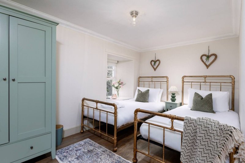 Bright twin bedroom with metal-frame beds, green wardrobe, and heart wall decorations