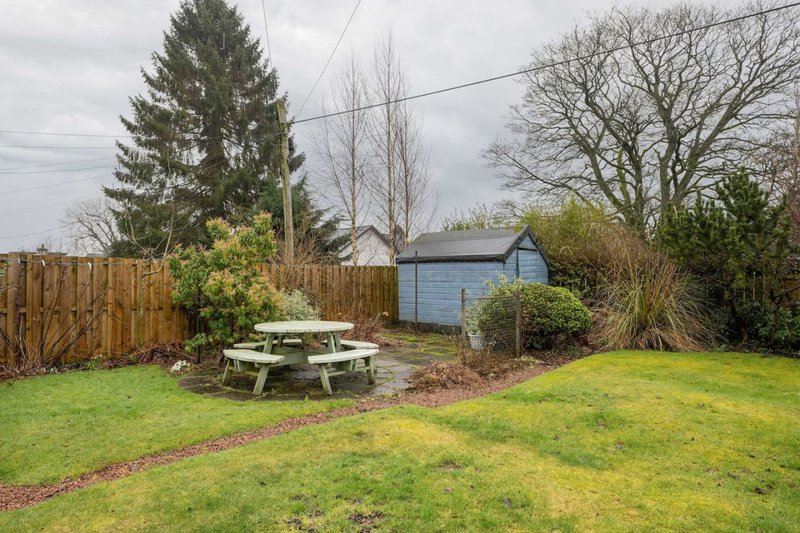 Garden with picnic table, shed, wooden fence, lawn and mature trees