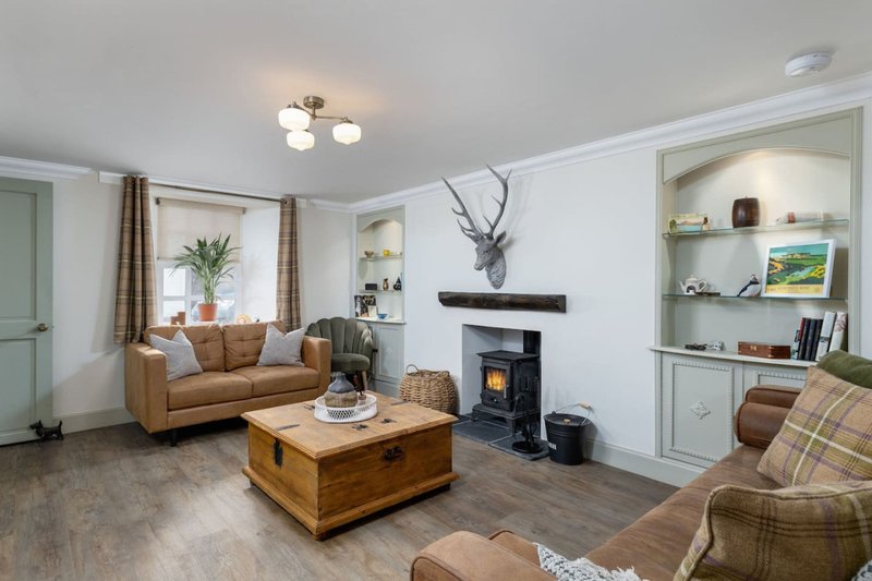 Bright living room with tan sofa, wood coffee table, fireplace, and built-in shelving