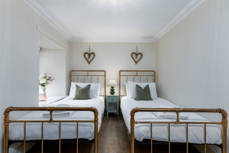 Twin bedroom with two metal-frame beds, white bedding, heart decorations and wooden flooring