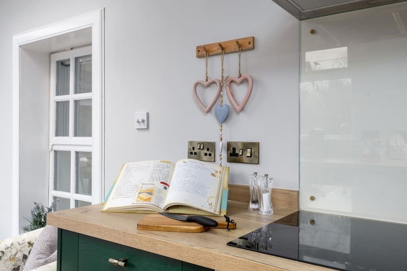 Desk workspace with open book, wooden organizer, heart decorations, and white door visible
