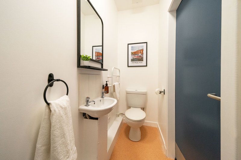 Small bathroom with sink, toilet, mirror, towel rail and orange floor