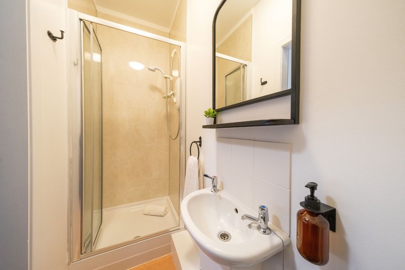 Clean bathroom with shower cubicle, round sink, mirror and toiletries