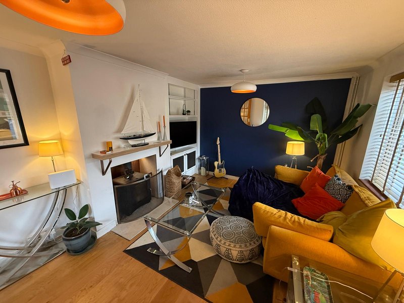 Modern living room with yellow sofa, dark blue feature wall, fireplace and wooden flooring
