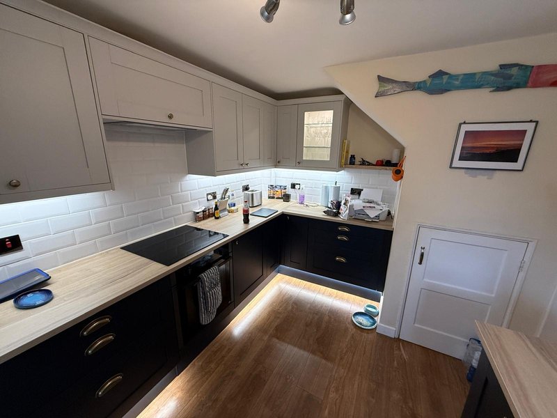 Modern kitchen with white and black cabinetry, white subway tile backsplash, wooden countertops, and hardwood flooring