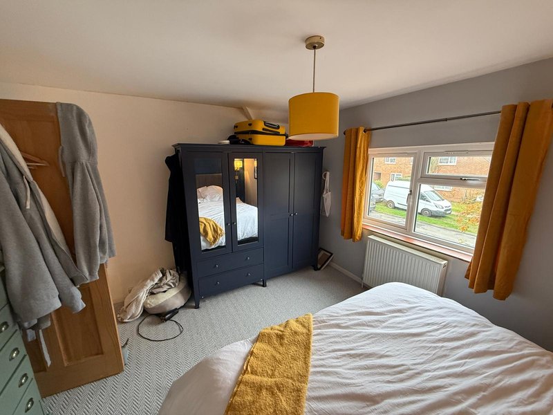 Bedroom with double bed, dark wardrobe, yellow pendant lamp and garden view