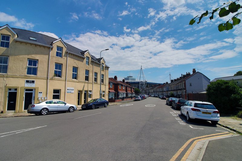 Yellow multi-story building on quiet street with parked cars and blue sky