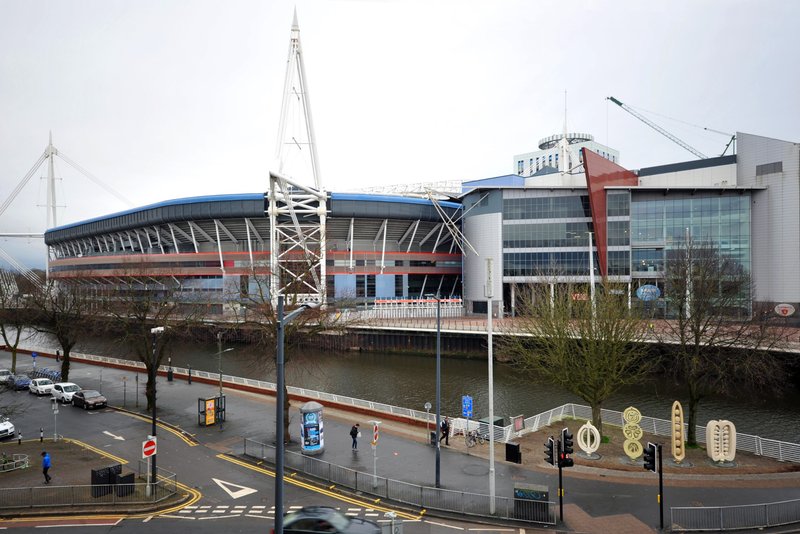 Large modern sports stadium beside river with contemporary architecture and urban surroundings