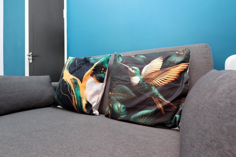 Modern living room with gray sofa, decorative bird-print cushions, and blue striped wall