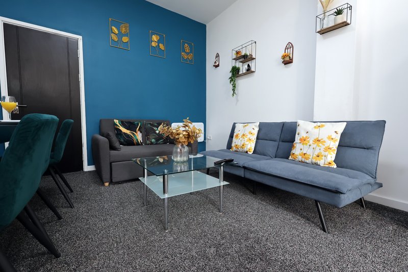Modern living room with blue and white walls, grey sofas, glass coffee table and decorative wall art