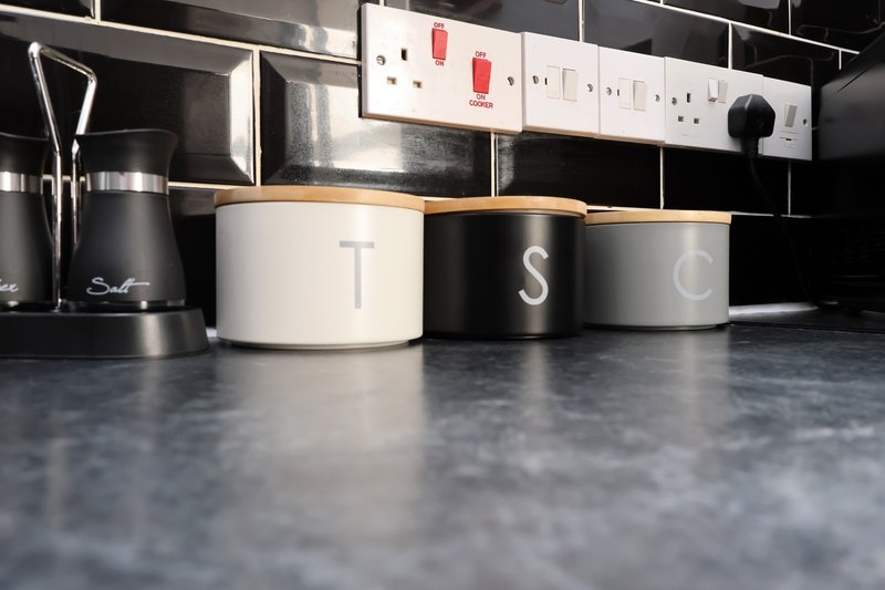 Modern kitchen countertop with storage containers, kettle, and wall-mounted electrical outlets