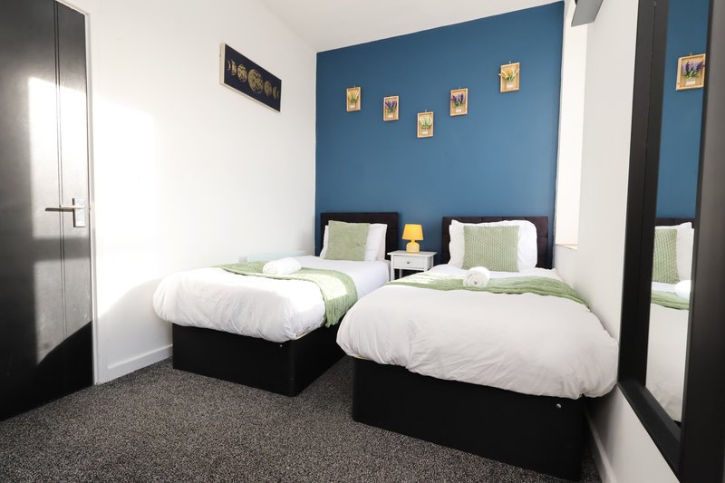 Twin bedroom with two single beds, blue accent wall, and modern furnishings