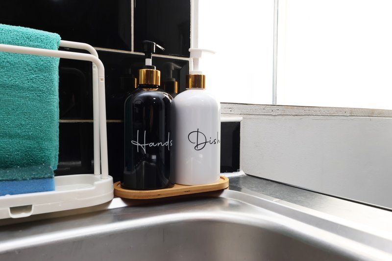 Modern bathroom sink with hand soap dispensers, towels and accessories on counter