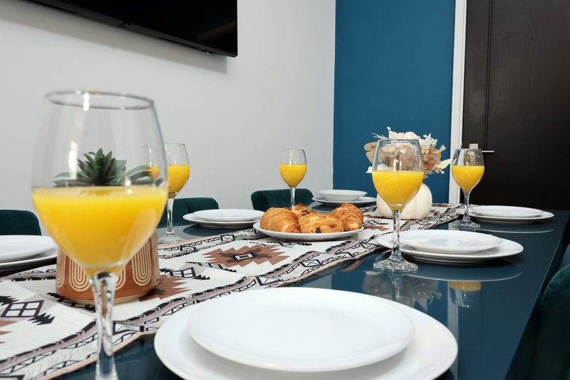 Dining table set with plates, glasses of orange juice, and pastries for breakfast