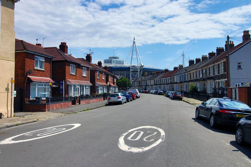 Street view of Victorian terrace houses with parked cars and distant cityscape