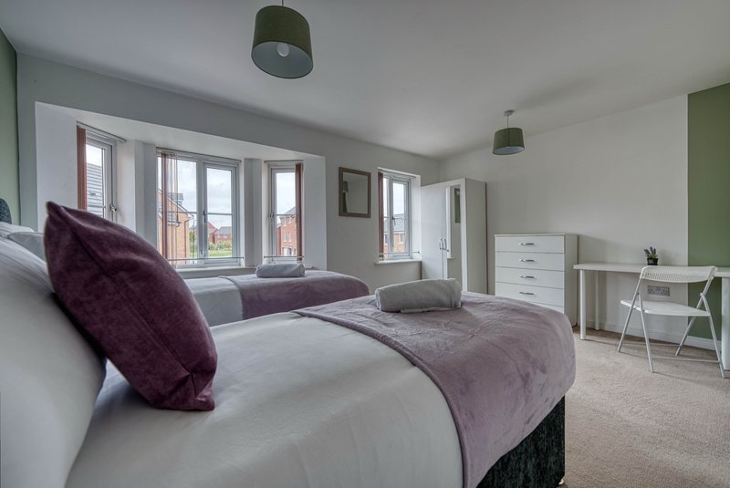 Modern bedroom with double bed, purple cushions, desk area and French doors with garden views