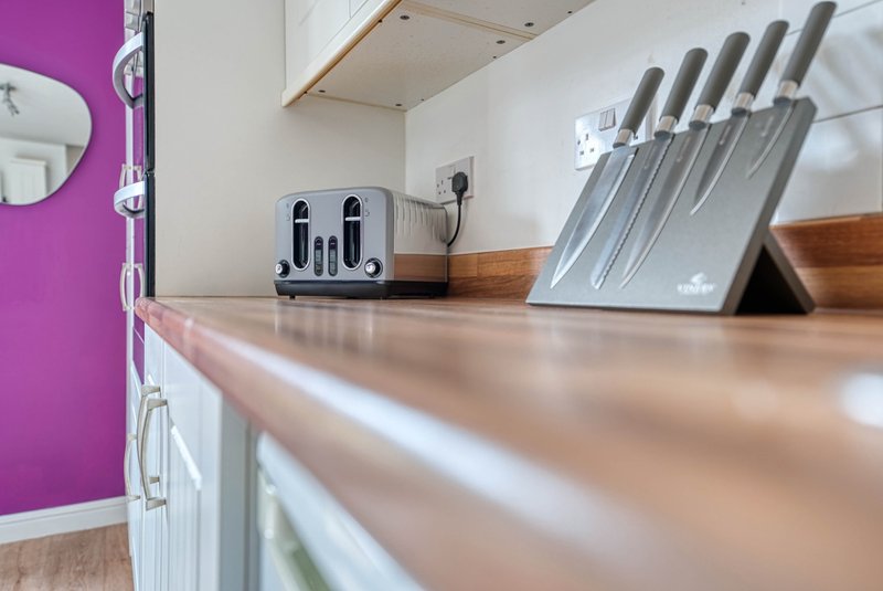 Modern kitchen counter with toaster, knife block, and purple accent wall