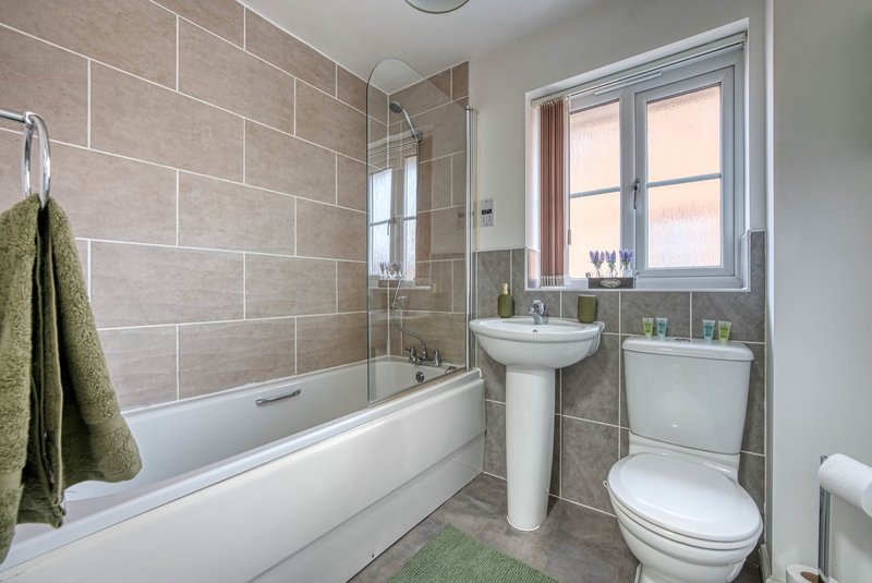 Modern bathroom with shower bath, pedestal sink, toilet and tiled walls