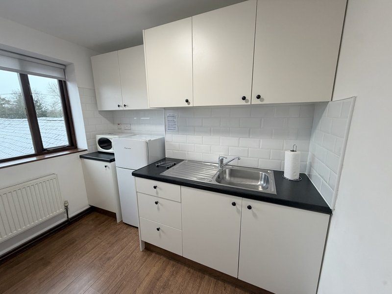 Clean white kitchen with black countertop, sink, and window overlooking garden