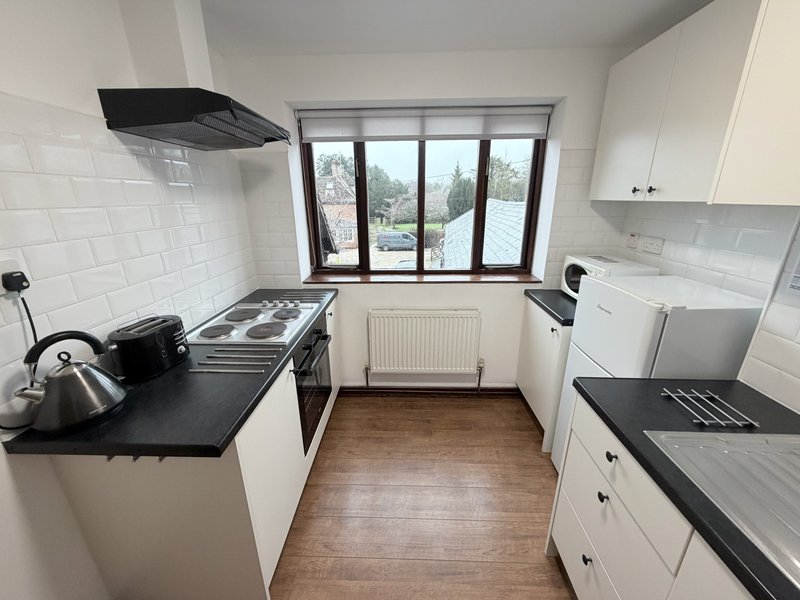 Modern kitchen with white cabinetry, black countertops, stainless steel appliances and window view