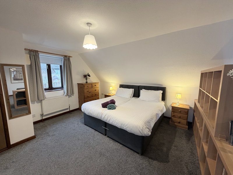 Bright bedroom with double bed, wooden nightstands, pendant light and window view