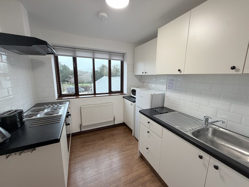 Modern kitchen with white cabinetry, stainless steel sink, wooden flooring and multi-pane window