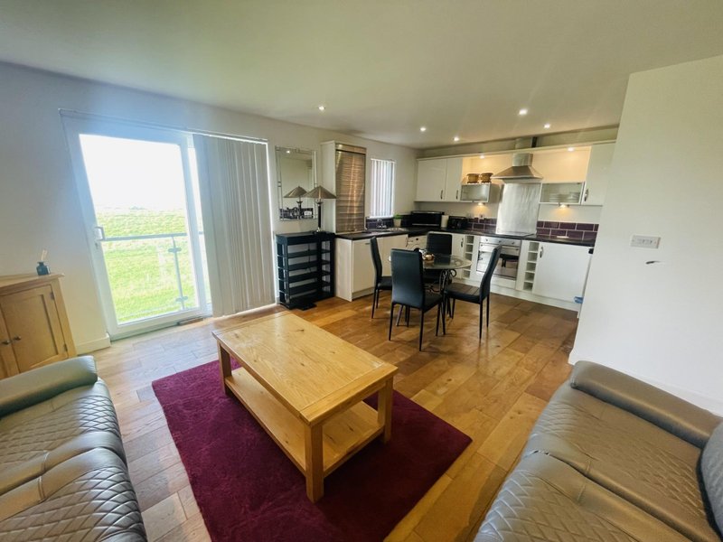 Open-plan living room and kitchen with wooden floors, dining table, and seating area