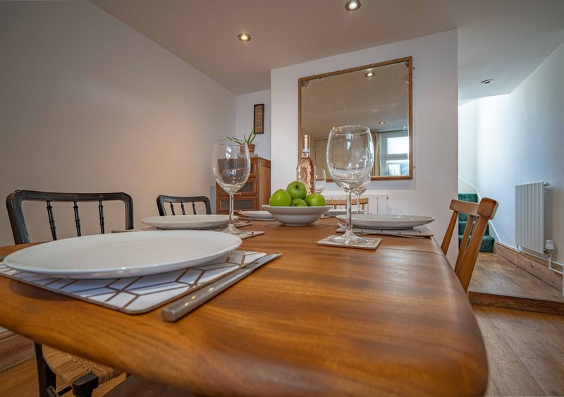 Dining room with wooden table, place settings, wine glasses, mirror and black chairs