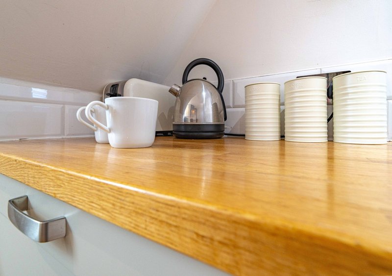 Kitchen shelf with kettle, white mugs and cream-colored storage containers
