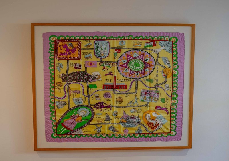 Framed decorative board game illustration with colorful pink and yellow design on white wall