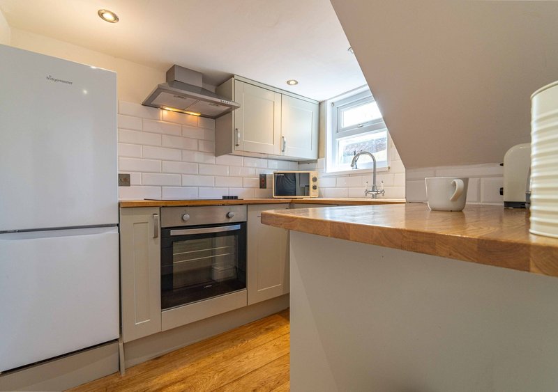 Modern kitchen with white cabinetry, wooden countertop, stainless steel appliances and subway tile backsplash