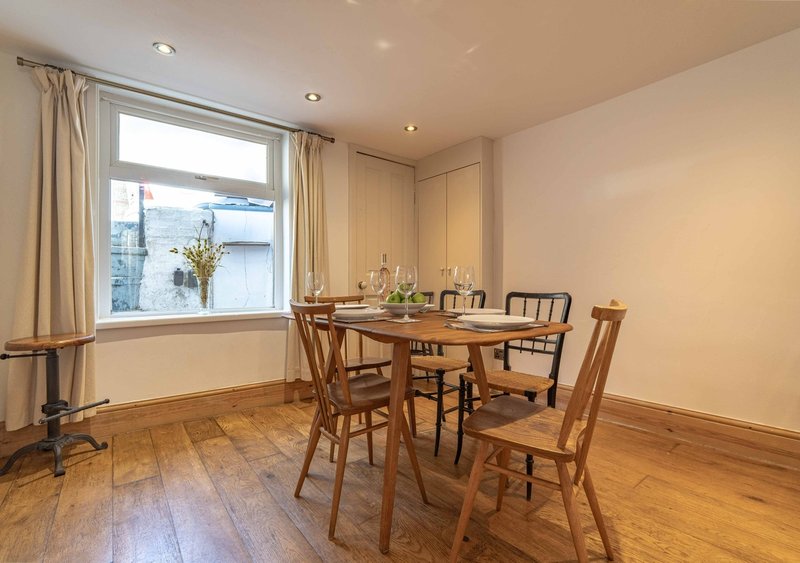 Dining room with wooden table, four chairs, large window with view, and wooden flooring