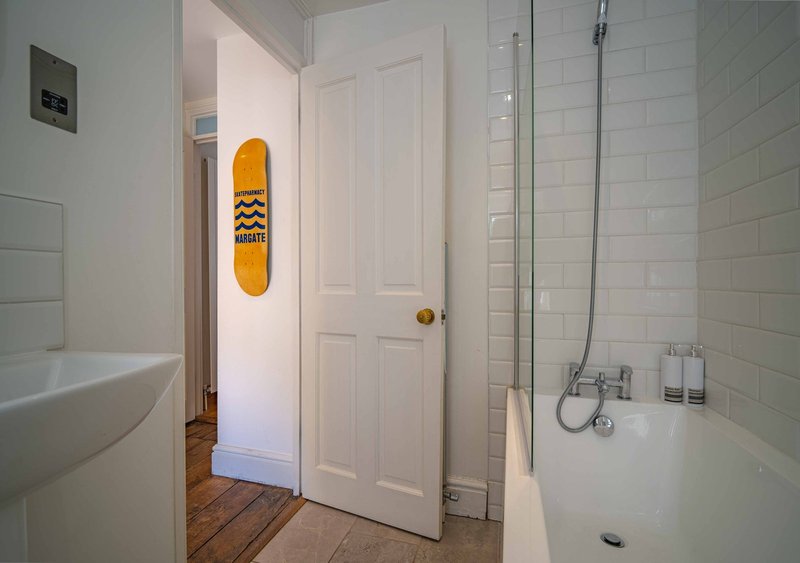 Clean bathroom with white subway tiles, sink, toilet, shower enclosure and yellow skateboard wall decor