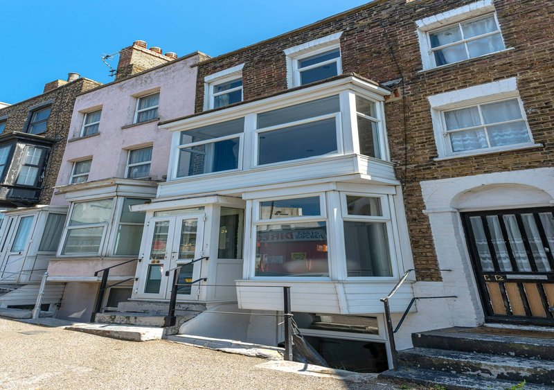 Terraced townhouse with white-framed shop front and residential upper floors