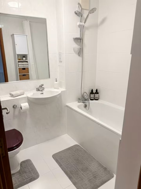 Clean white bathroom with sink, mirror, toilet, bathtub and shower fixtures