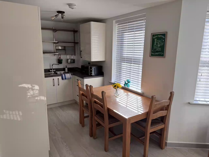 Open-plan kitchen and dining area with wooden table, chairs, and fitted kitchen units