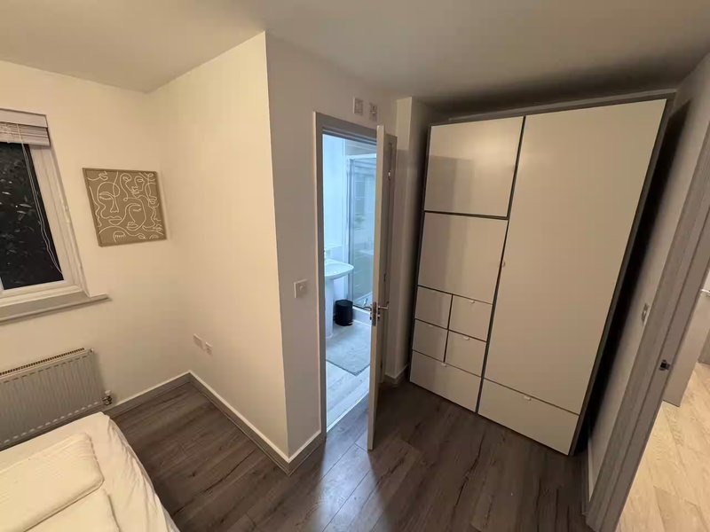 Bedroom with wooden floor, large built-in wardrobe, radiator and window