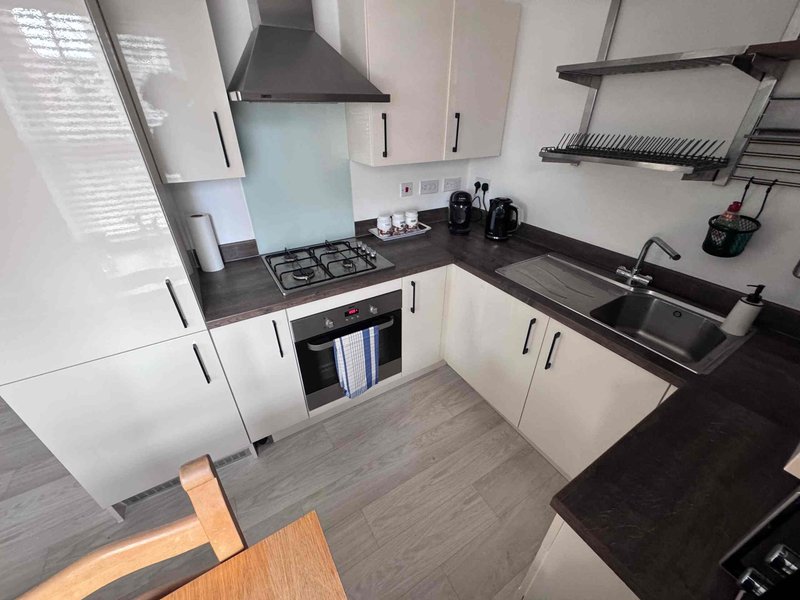 Modern kitchen with white cabinets, black countertops, gas hob, and stainless steel appliances