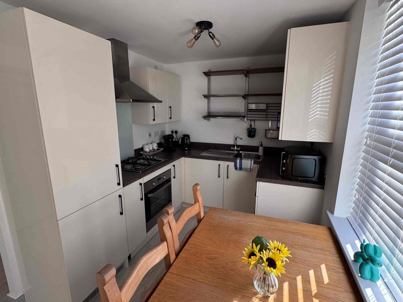 Modern kitchen with white cabinets, black countertops, wooden dining table with yellow flowers
