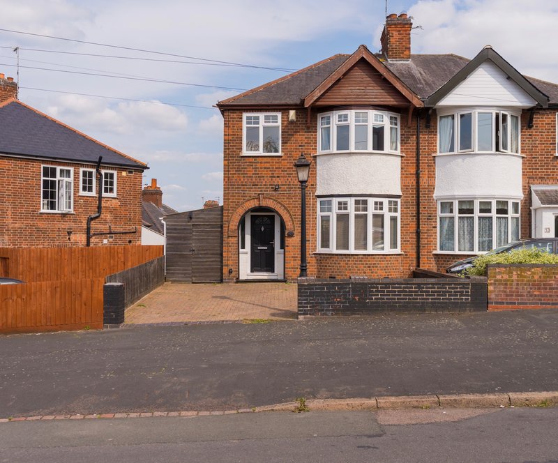 Brick semi-detached house with driveway, front garden, and bay windows
